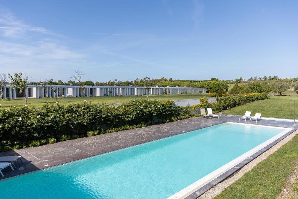 a swimming pool with two chairs and a house at Bom Sucesso Resort in Vau