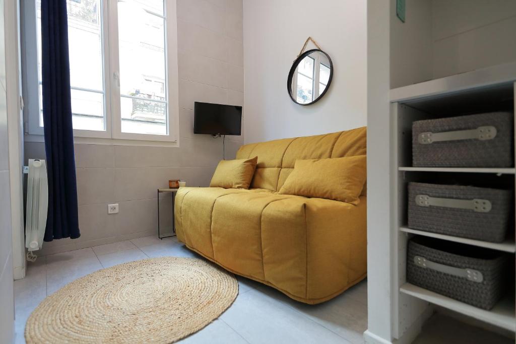 un canapé jaune dans un salon avec une horloge dans l'établissement Stay in the Heart of Paris, à Paris