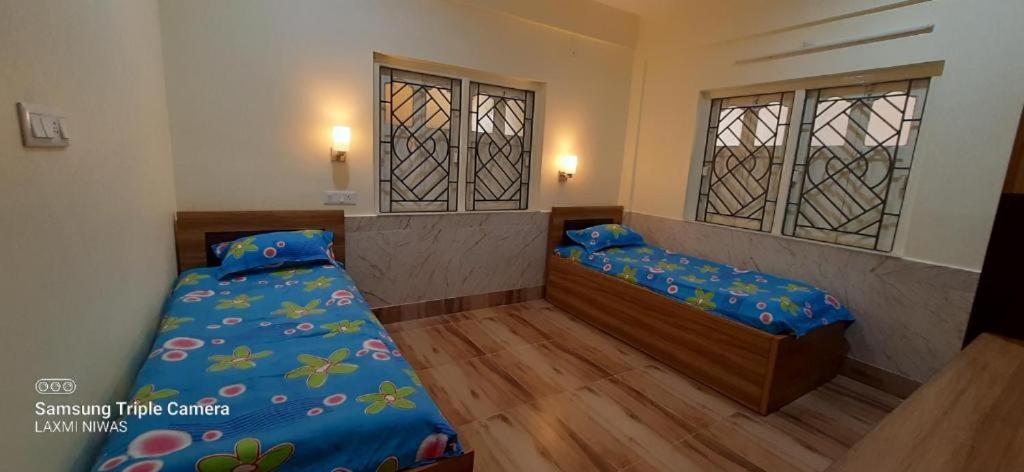 a bedroom with two beds and two windows at Sengar's Inn in Gwalior