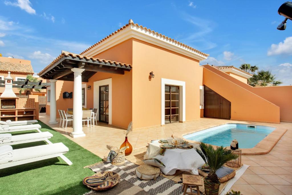 een achtertuin met een zwembad en een huis bij Villa Corralejo in Corralejo