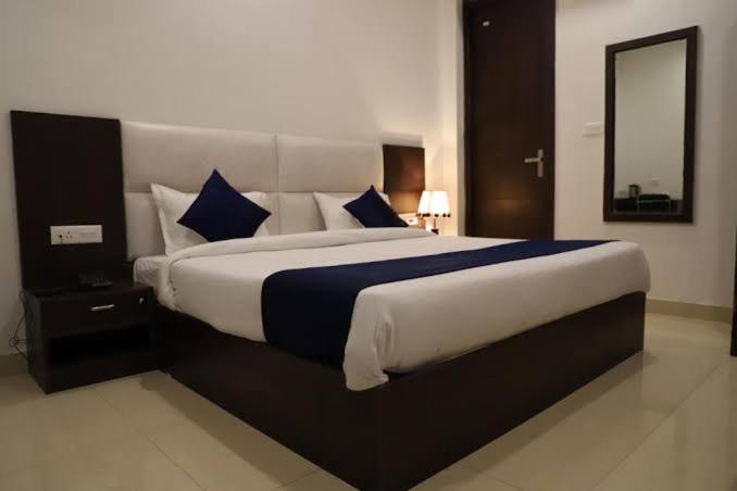 a bedroom with a large bed with blue and white pillows at Hotel Kings Comfort in Tājganj