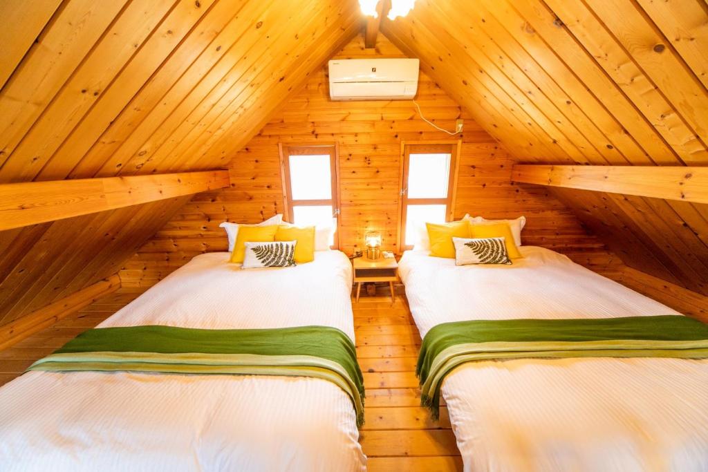 two beds in a log cabin bedroom with wooden walls at [Sumoto City] Log house Gosyokumachi1 - Vacation STAY 14162 in Sumoto