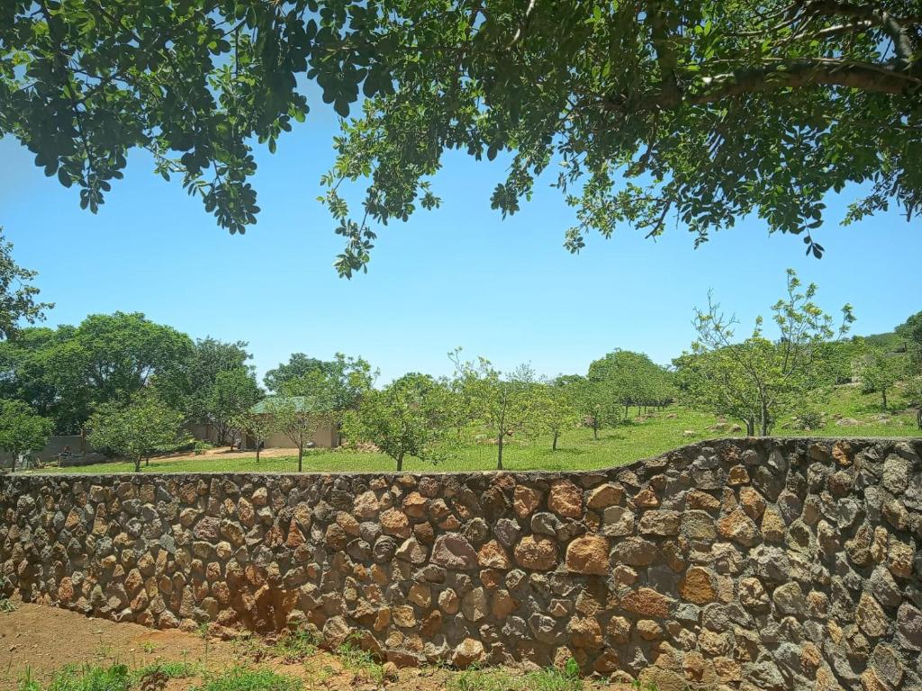 a stone retaining wall with trees in the background at Two Bed Two Bath Cottage in Bulawayo