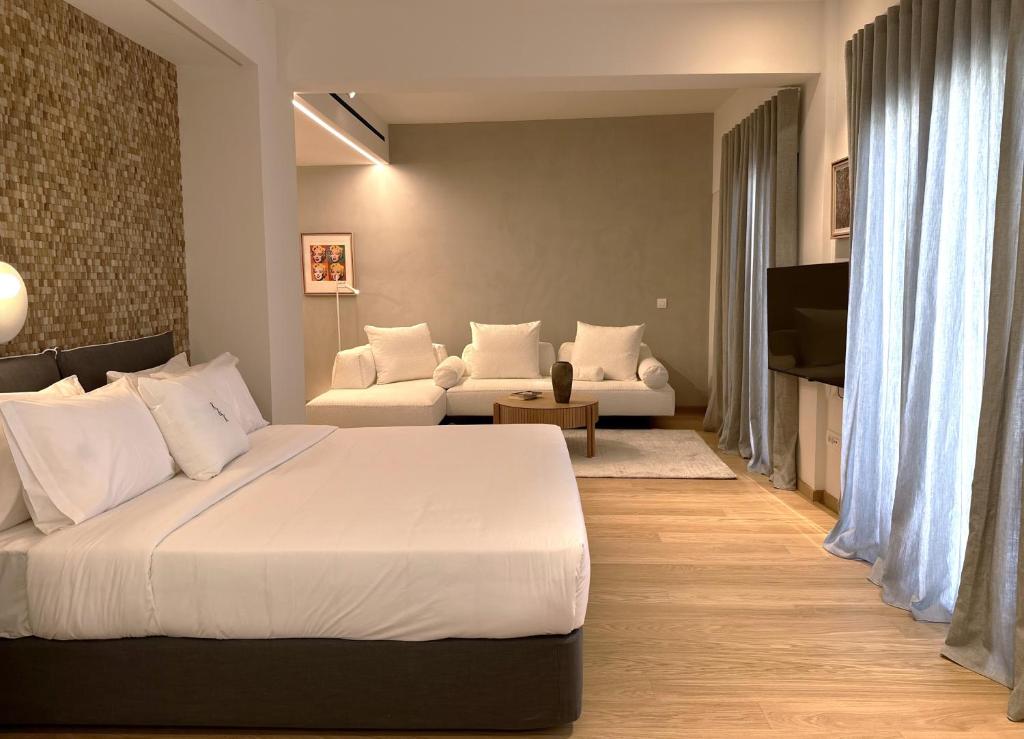 sypialnia z dużym białym łóżkiem i kanapą w obiekcie AIONION RESIDENCES by K&K w Atenach