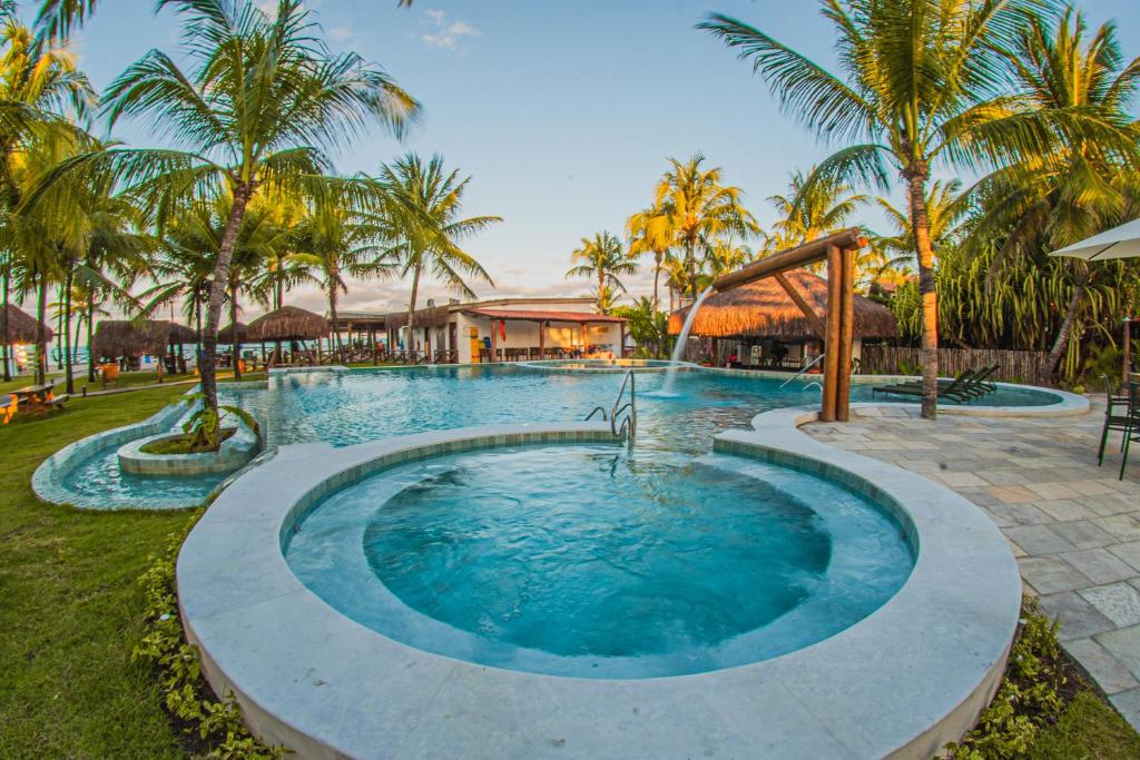 a pool at a resort with palm trees at Privê Pontal de Maracaipe in Porto De Galinhas