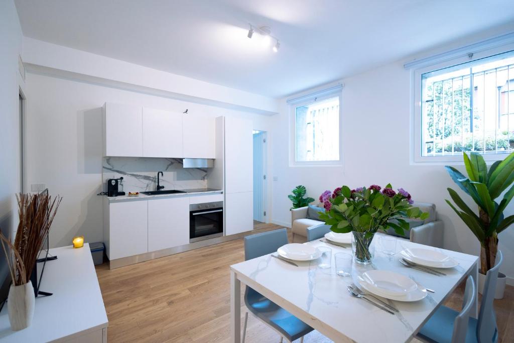 uma cozinha e sala de estar com uma mesa branca e cadeiras em tHE Urban Wildlife - San Babila Home em Milão