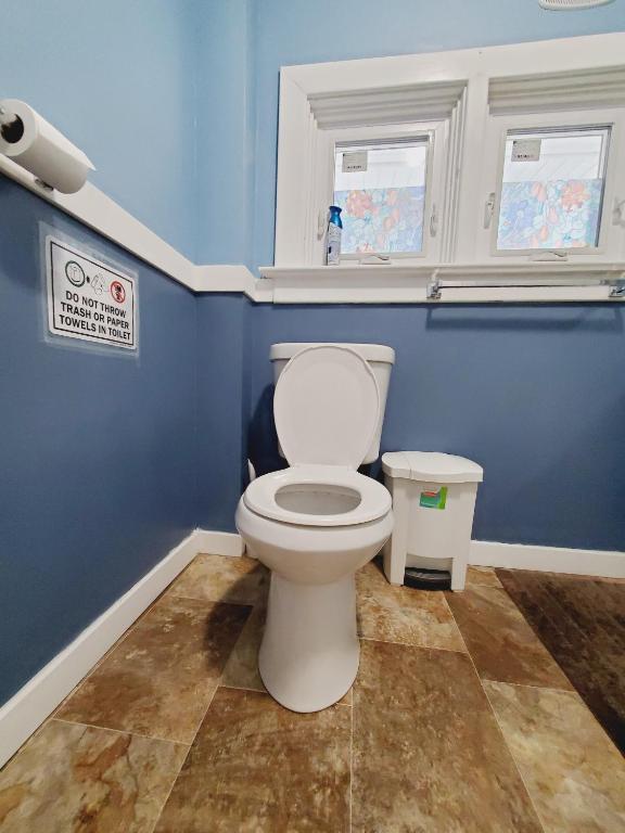 a bathroom with a white toilet and blue walls at Merj's Guest House in Wolesly in Winnipeg