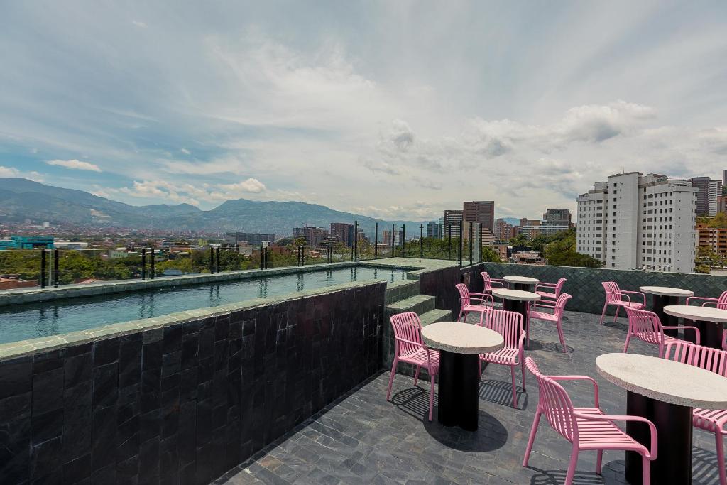 eine Reihe von Tischen und Stühlen auf einer Dachterrasse in der Unterkunft Hotel Poblado Park in Medellín