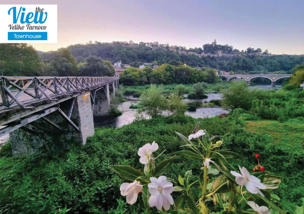 a wooden bridge over a river with flowers at The View Veliko Tarnovo Townhouse in Veliko Tŭrnovo