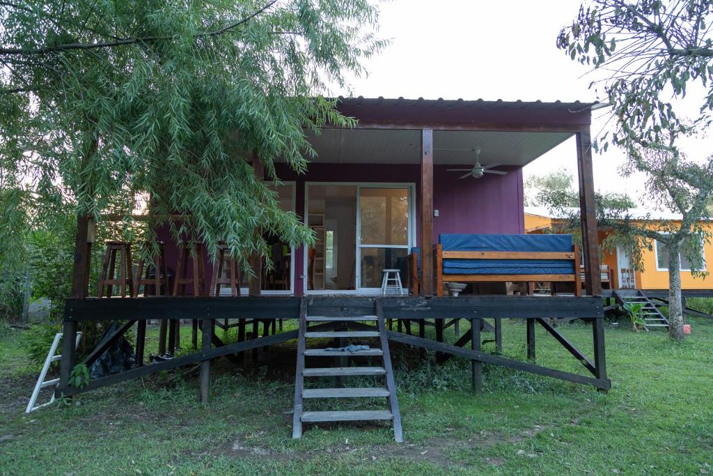 une petite maison avec une terrasse couverte et une échelle dans l'établissement Cabañas Chaná y Timbú, à Dique Luján