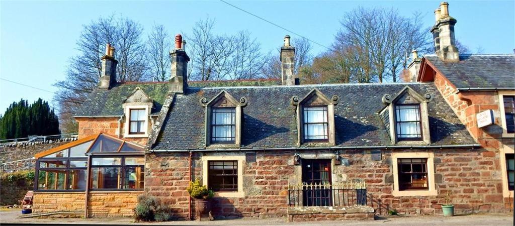 een oud stenen huis met een zwart dak bij The Ben Bhraggie Inn in Golspie