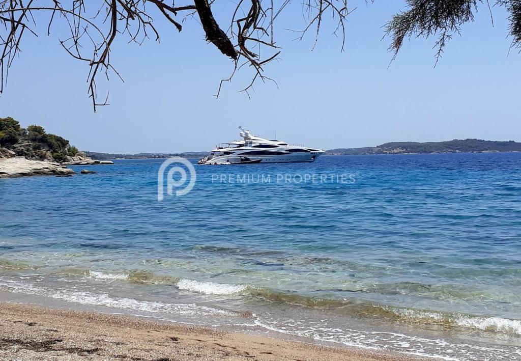 a boat in the water next to a beach at Villa Tranquility - Walk to the Beach with Infinity Pool in Porto Heli
