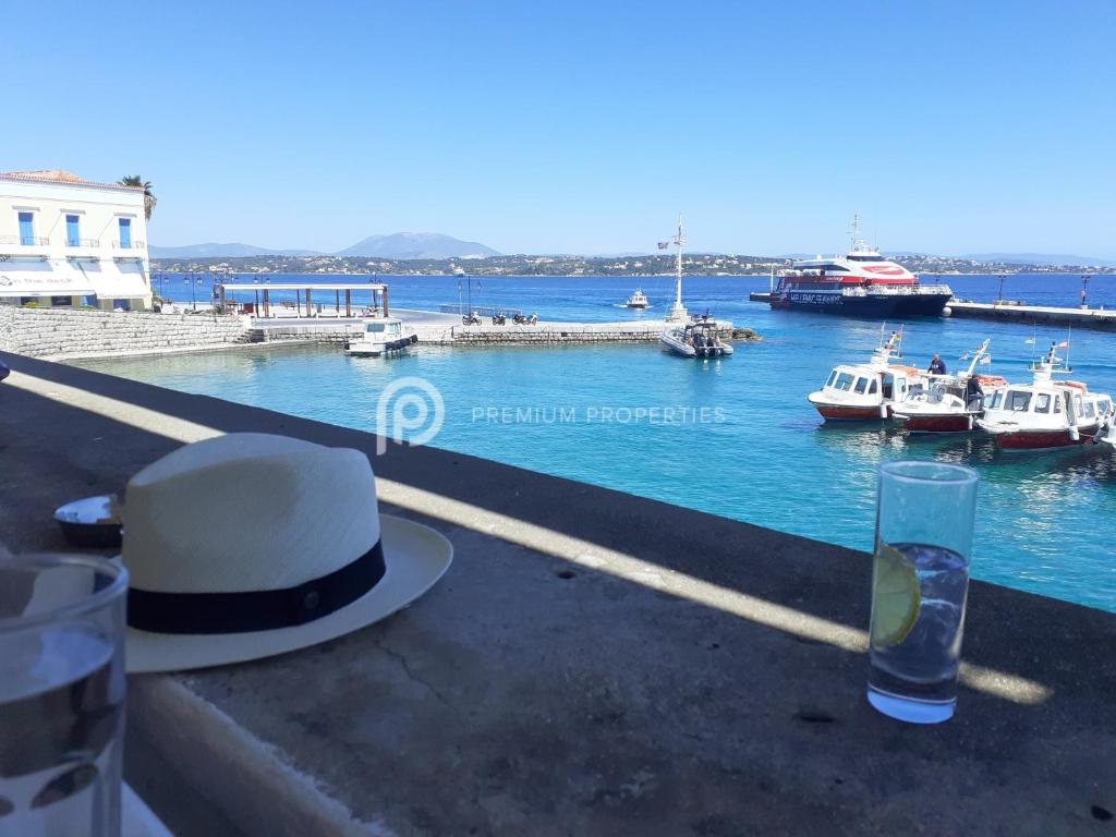 a hat and a glass sitting on a ledge near the water at Villa Tranquility - Walk to the Beach with Infinity Pool in Porto Heli