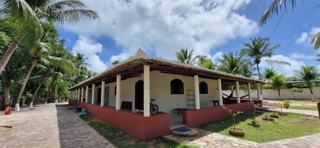 een klein wit gebouw met palmbomen op de achtergrond bij Pousada Caseira Varanda da Maya in Maxaranguape
