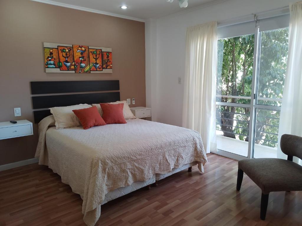 Un dormitorio con una cama con almohadas rojas y una ventana en Aparts Lio Nell en Colón