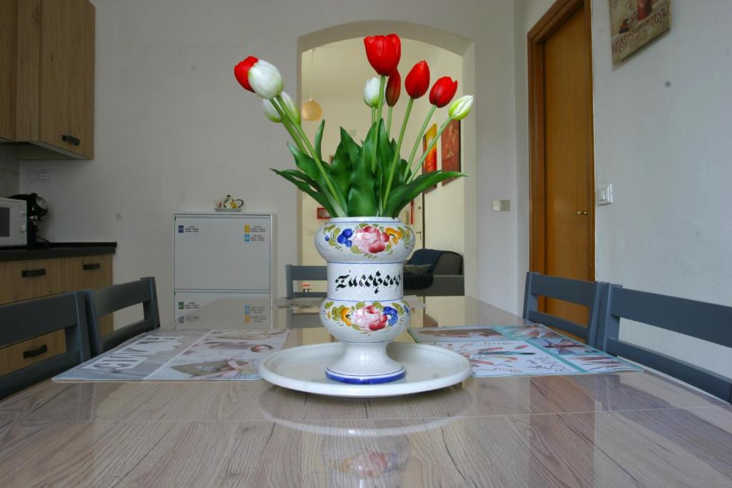 een vaas gevuld met rode en witte bloemen op een tafel bij Casa Brin in La Spezia