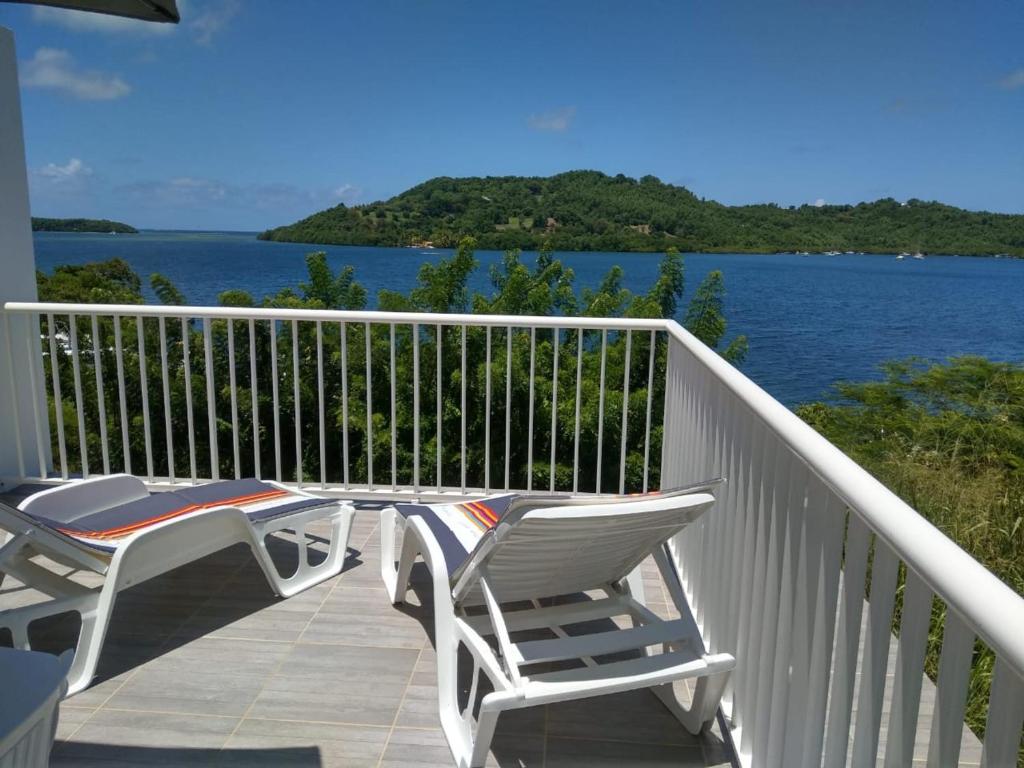 2 stoelen en een tafel op een balkon met uitzicht op het water bij Studio avec vue sur la mer terrasse amenagee et wifi a Le Robert in Le Robert