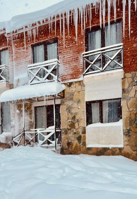 a building covered in snow with icicles hanging from it at Memories House in Bakuriani