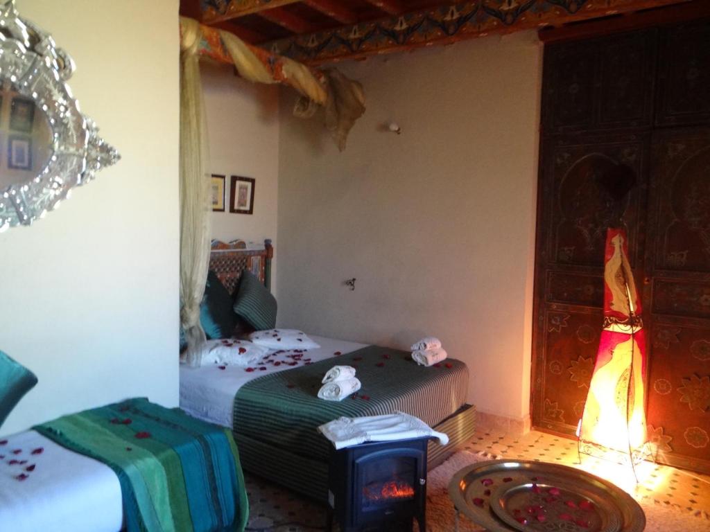 a bedroom with two beds and a table and a mirror at Riad Rchacha in Fès