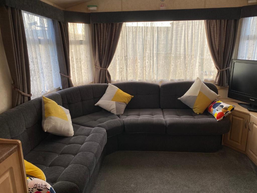 a living room with a gray couch with pillows at Static van on Smallgrove in Ingoldmells in Skegness