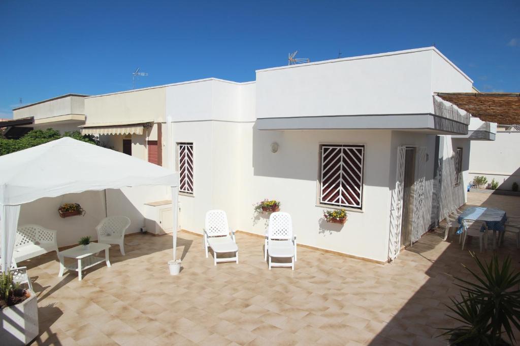 Casa blanca con sillas y sombrilla blanca en Il mare di Totino - Seaside guest house - Torre San Giovanni, en Torre San Giovanni