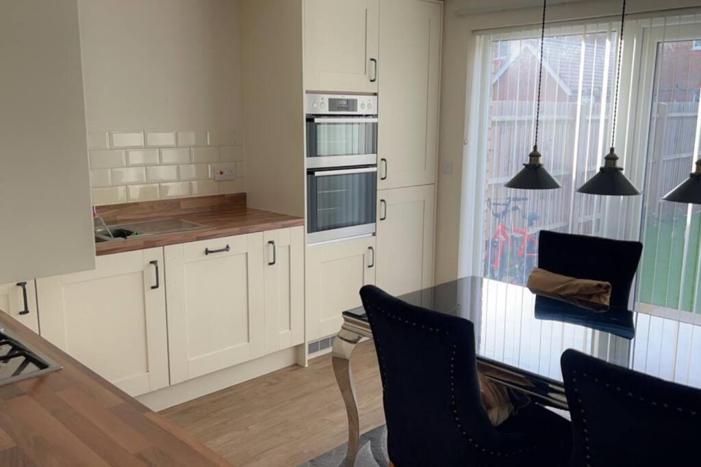 uma cozinha com armários brancos e uma mesa e cadeiras em The American style house em Kent