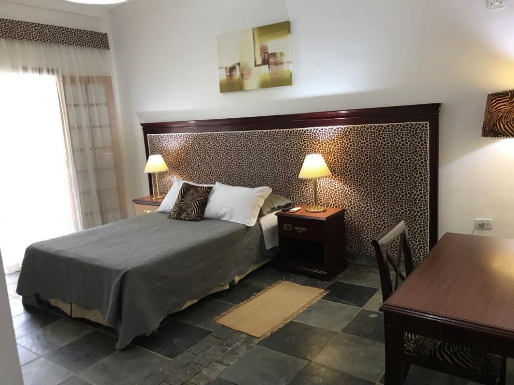 a bedroom with a bed and a table and two lamps at hotel fazenda encanto in Guararema