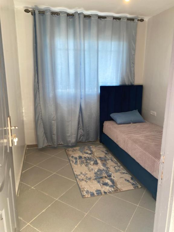ダフラにあるعقار الشرق الداخلةのベッドルーム1室(カーテンとラグ付きのベッド1台付)