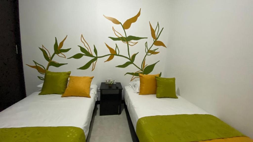 two beds in a room with green and yellow pillows at Lindos Apartamentos Amoblados con piscina in Montenegro