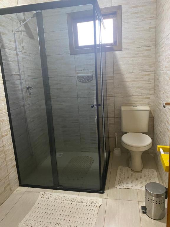 a bathroom with a glass shower with a toilet at Chalé Guadalupe - Condomínio Altos da Serra in Bom Jardim da Serra