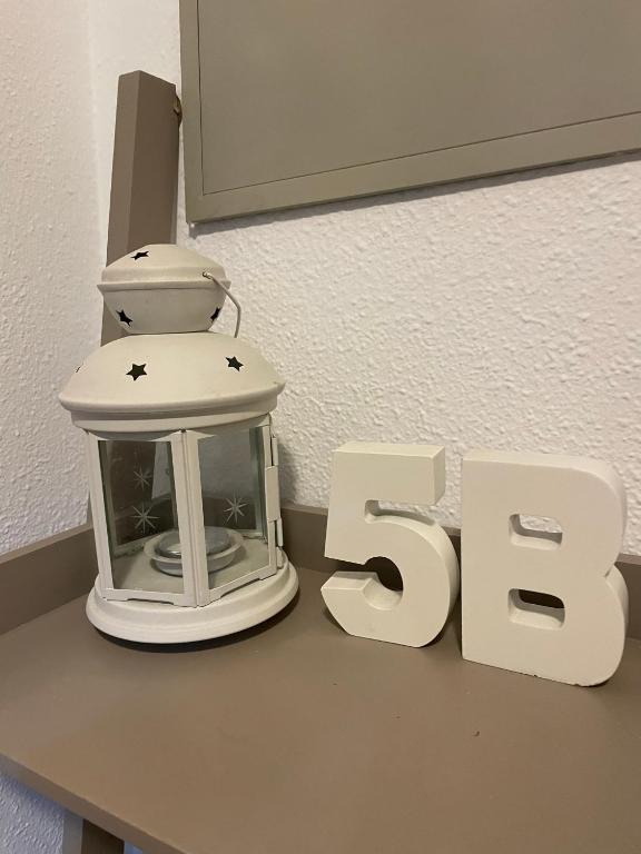 Hotel Las 5 Bes- Estudio bed&breakfast, a white lantern sitting on a table next to a sign at Las 5 Bes- Estudio bed&breakfast in Valladolid