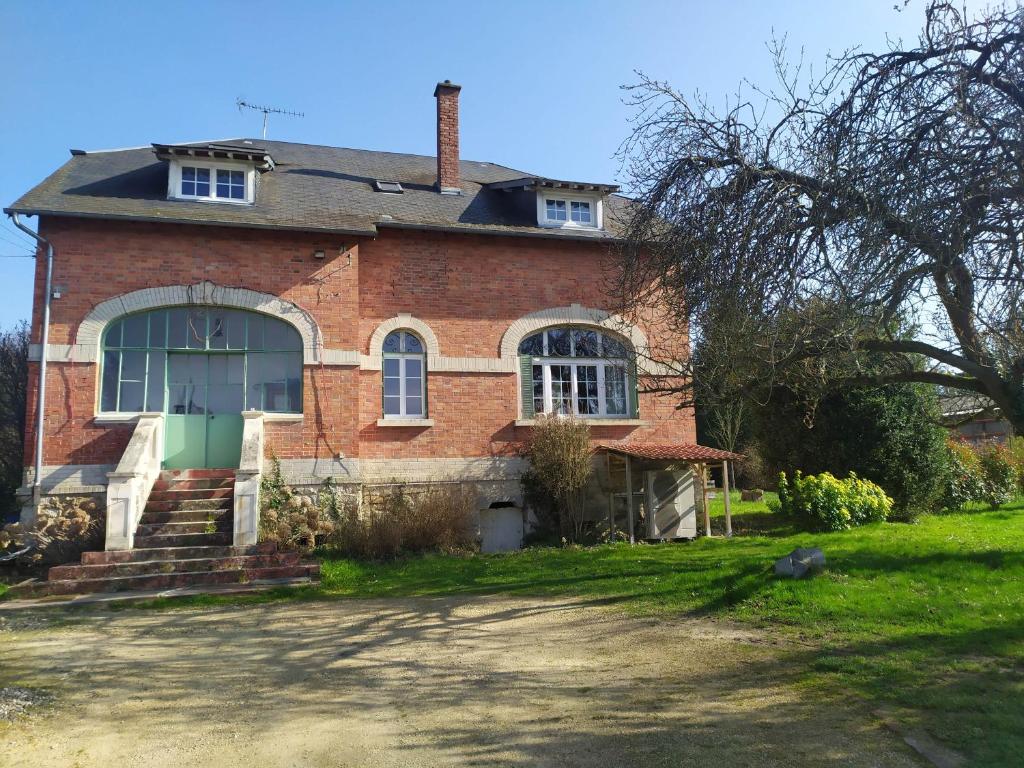 une maison en briques avec une porte verte sur une cour dans l'établissement Le gite du lavoir, à Suzy