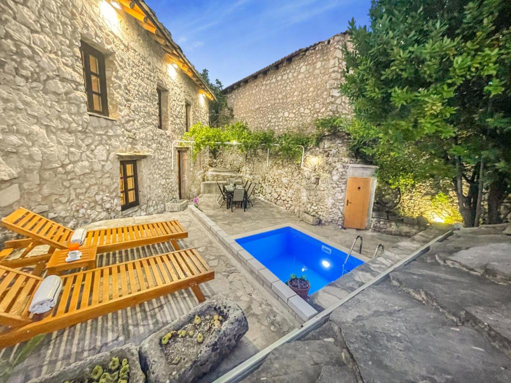 um pátio de uma casa de pedra com uma piscina azul em Villa Historic Pocitelj with pool and incredible views on the river and landmarks em Počitelj