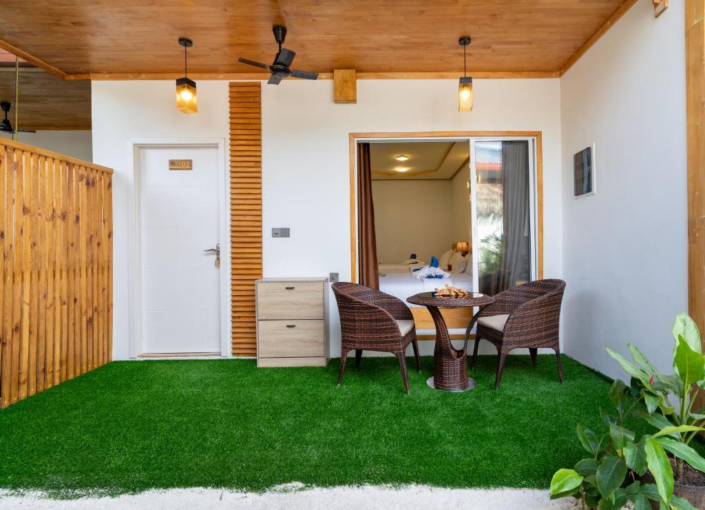 d'une terrasse avec de la pelouse verte, une table et des chaises. dans l'établissement Tropico villa, à Ukulhas