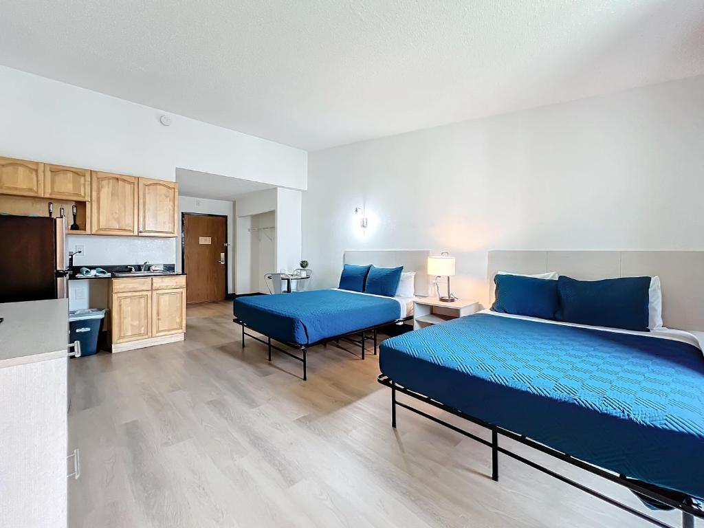 a bedroom with a blue bed and a kitchen at Stayable Kissimmee East in Kissimmee