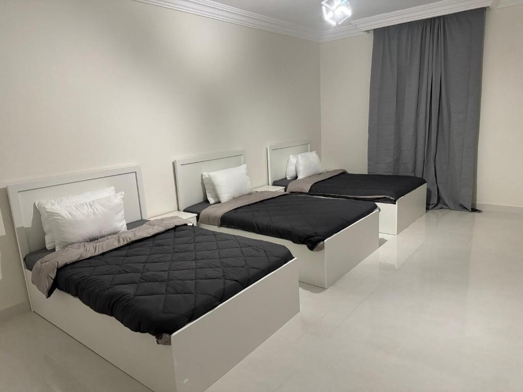 Almadina Apartemetns في المدينة المنورة: سريرين في غرفة بيضاء ذات أغطية سوداء