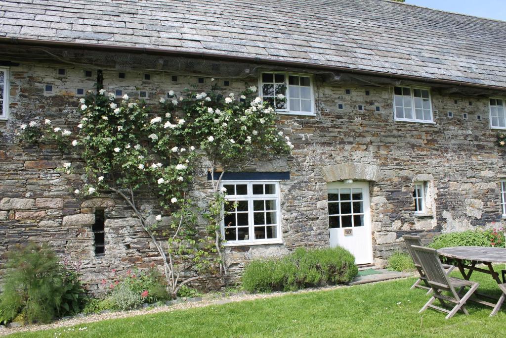 a stone house with a table and a tree with white flowers at Dick Cottage in Bodmin