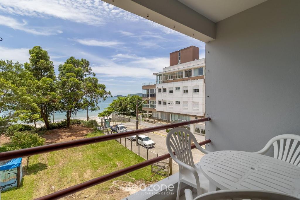 einen Balkon mit einem Tisch und Stühlen sowie Straßenblick in der Unterkunft Sossego frente mar com vista para a ilha CCA201 in Florianópolis