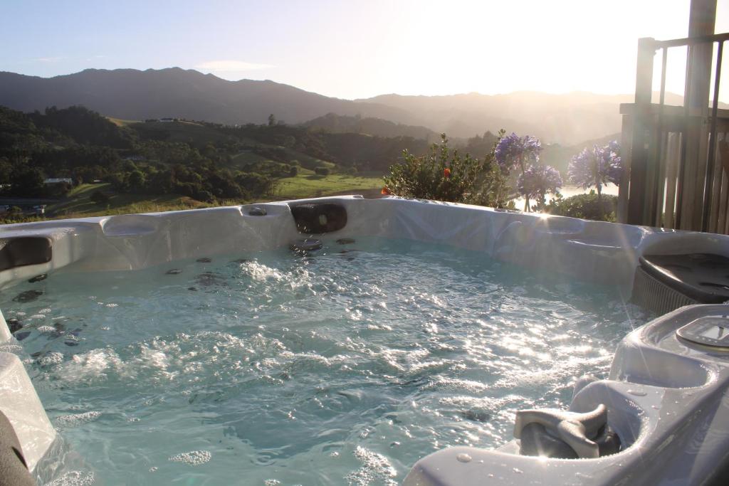 a jacuzzi tub with a view of the mountains at Coromandel Seaview Motel in Coromandel Town