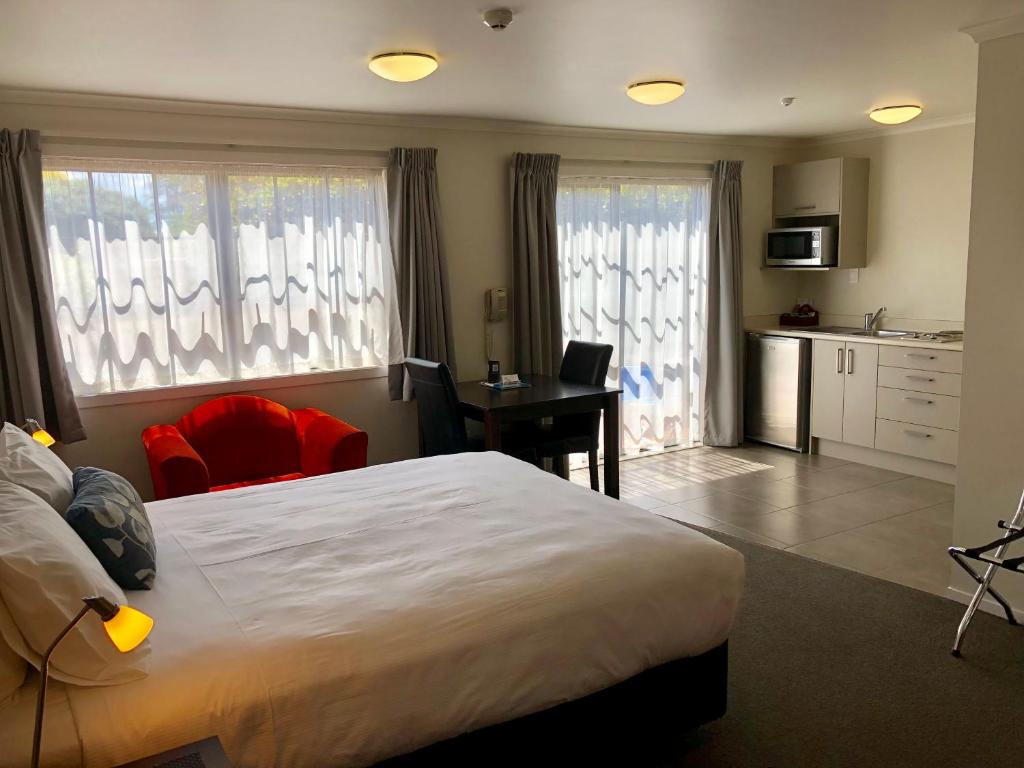 een slaapkamer met een bed, een bureau en een keuken bij Arena Court Motel in Hamilton
