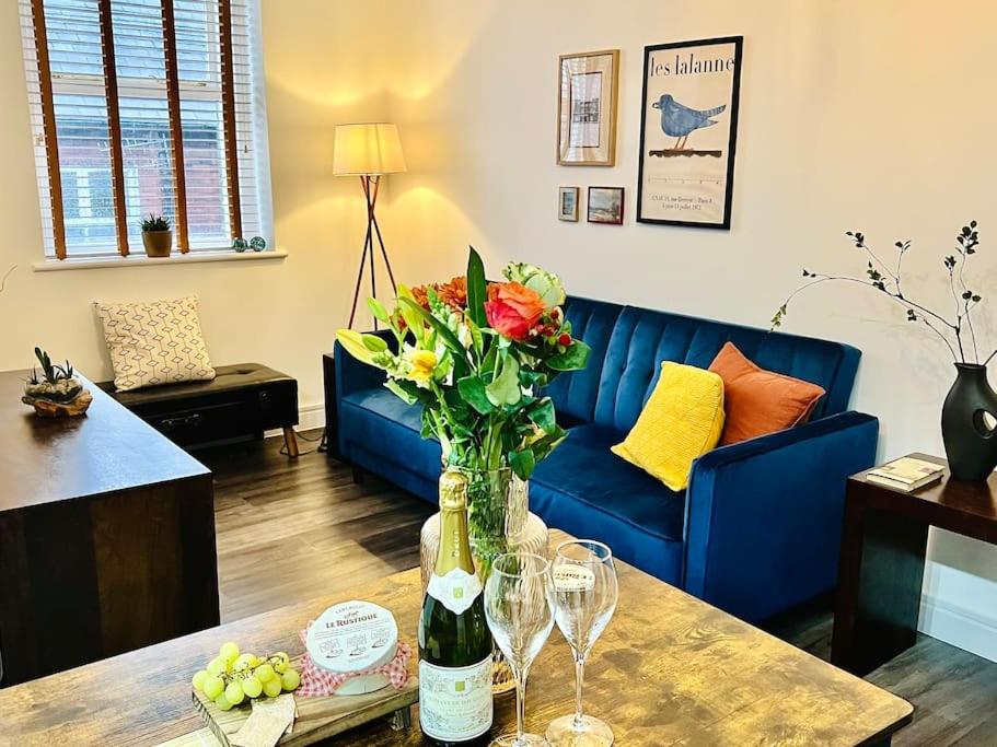 uma sala de estar com um sofá e uma mesa com um vaso de flores em Central Buxton apt in Spring Gardens em Buxton