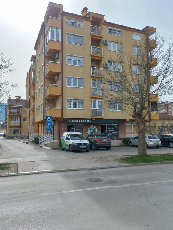 un gran edificio amarillo con coches aparcados en un aparcamiento en Lavander, en Banja Luka