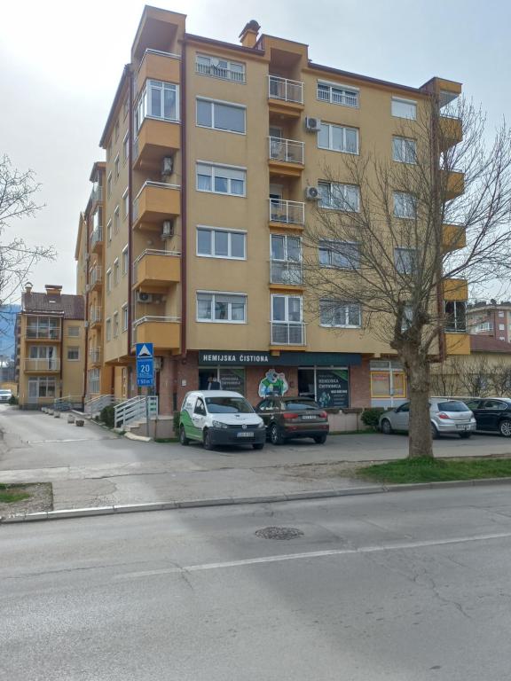 a large yellow building with cars parked in a parking lot at Lavander in Banja Luka