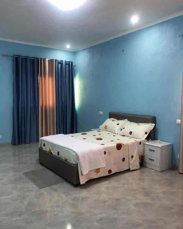 um quarto com uma cama grande num quarto azul em Guest House Meg Alfa em Luanda
