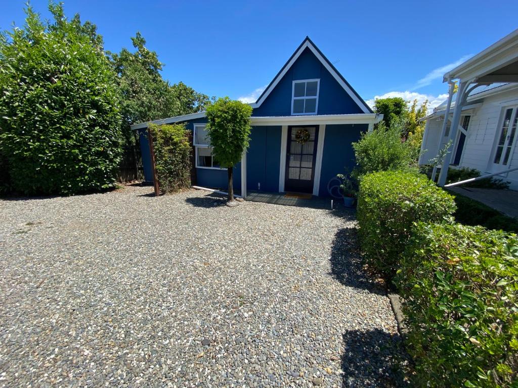a blue house with a gravel driveway at The cottage at the Gables in Motueka