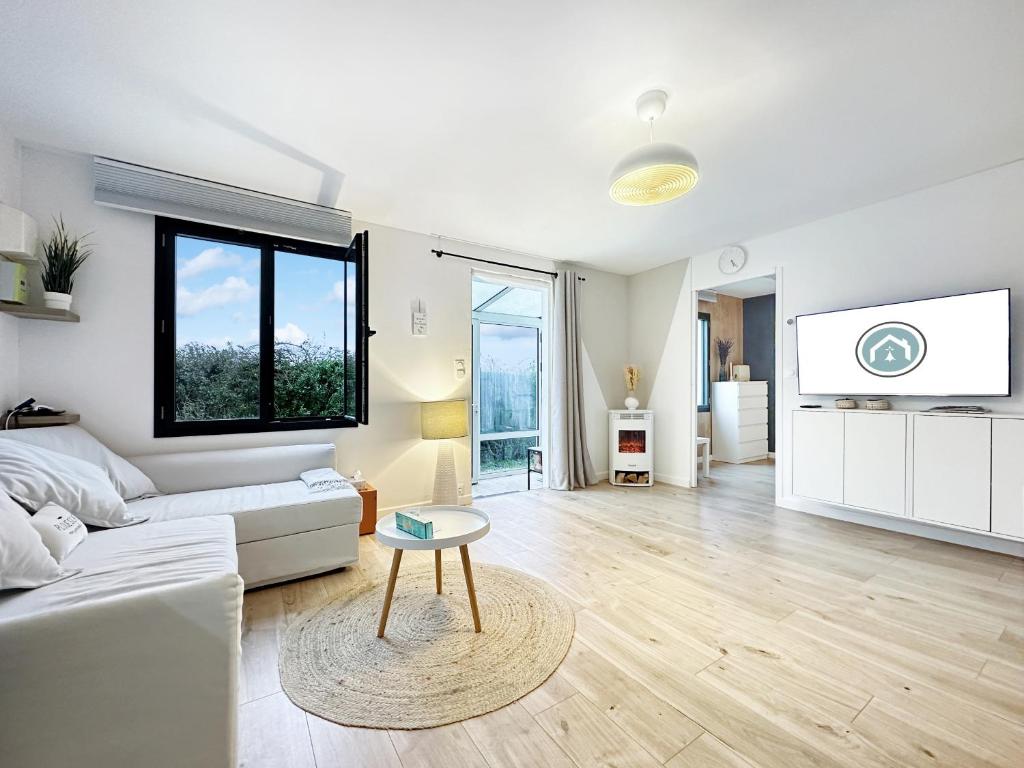 een woonkamer met een witte bank en een tafel bij La Pommedepin Ravissante maisonnette avec jardin in Plouescat