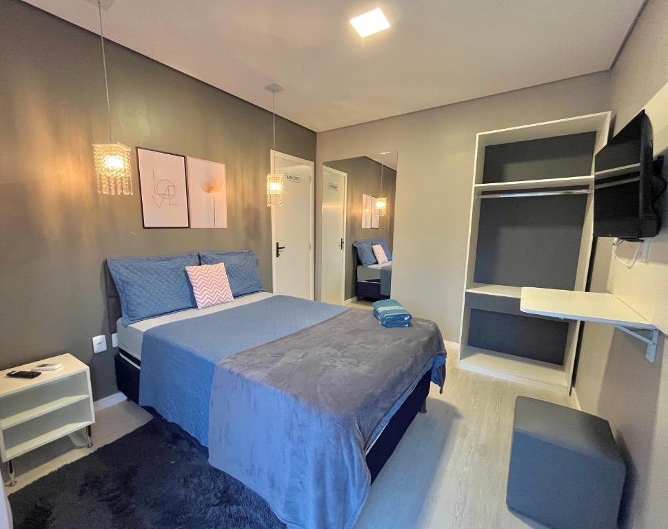 een slaapkamer met een blauw bed en een televisie bij Hotel Residencial Manaus - Flores in Manaus