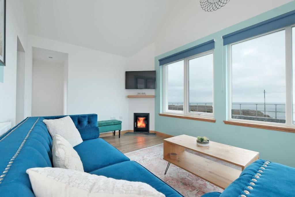 a blue couch in a living room with a fireplace at Cliff Top Cottage with Sea Views in Portknockie