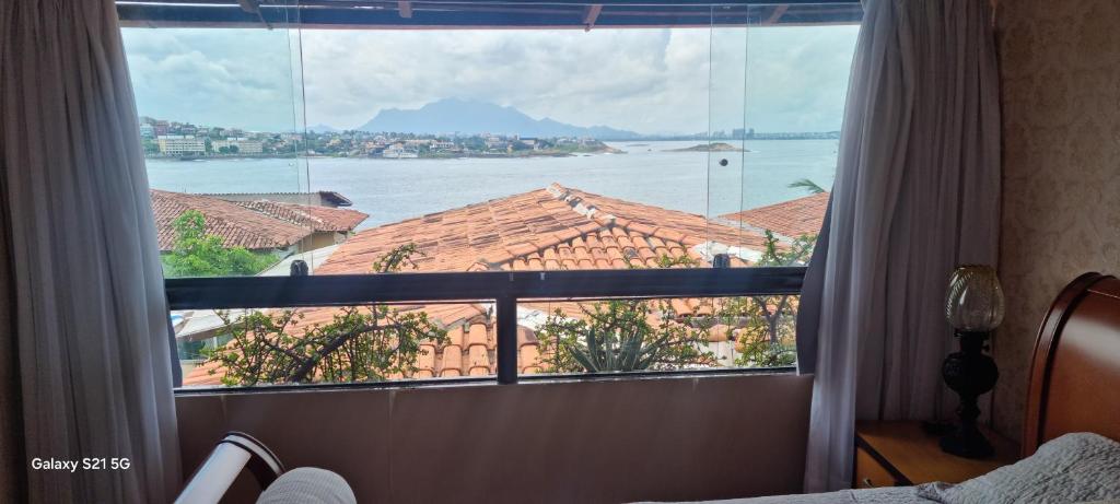 a bedroom with a large window with a view of the water at Pousada do Farol Bar e Restaurante in Vila Velha