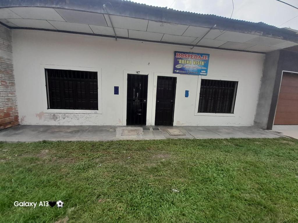 - un bâtiment blanc avec deux portes et un panneau dans l'établissement HOSPEDAJE BUENA VISTA IQUITOS, à Iquitos